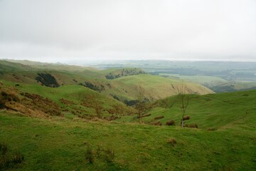 Fototapeta premium Green Fields on a Cloudy Day with Atmospheric Haze - Serene Landscape Photo