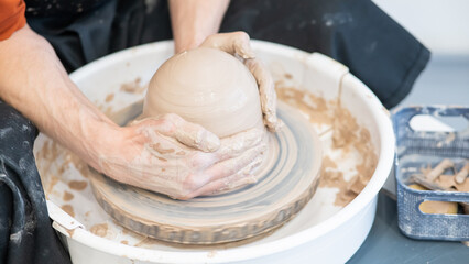 Close-up of a potter's hands working on a pottery wheel. 