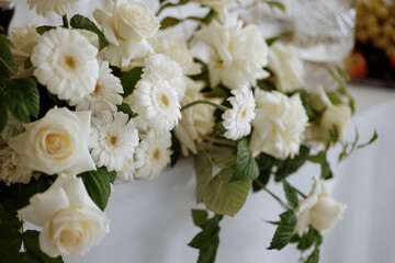 A bouquet of white roses and daisies. The roses are the main focus of the image, with their white petals and green stems. The daisies are smaller and more spread out