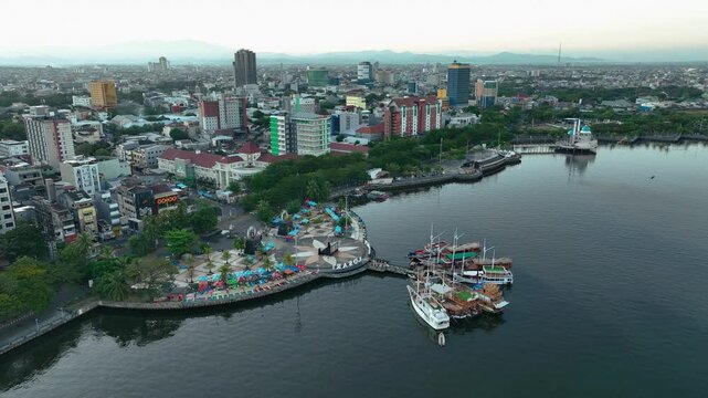 INDONESIA - 9.4.2024 - Excellent aerial footage swooping down towards boats docked at an urban harbor of Makassar, Indonesia.