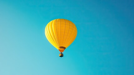 Fototapeta premium A yellow hot air balloon floating gracefully in a clear blue sky, symbolizing adventure and exploration.