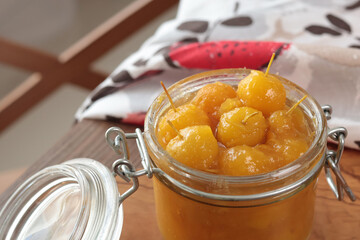 Glass jar of apple jam on wooden olive board. Homemade fruit jams from garden. Kitchen interior and organic food. 