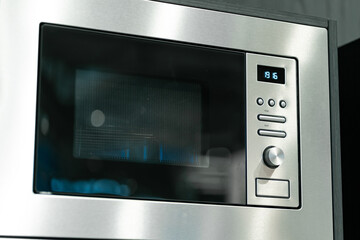 A built-in microwave oven with a digital display, seamlessly integrated into a light wooden kitchen...