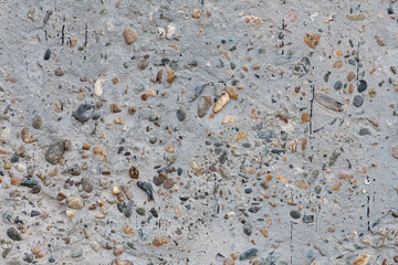 Texture of concrete surface with multicolored pebbles. Monolithic concrete wall with multicolored pebbles, stained with bitumen, high resolution.