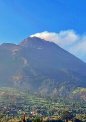 view of mount merapi with green valley and a house below