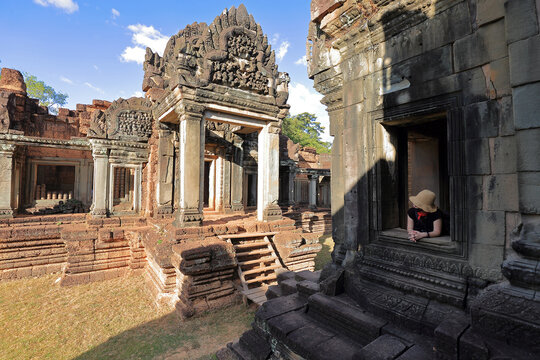 Banteay Samre Temple, Siem Reap, Cambodia - December 15, 2019: A woman staring out the window of a stone ruins.