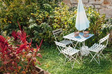 Petit salon de jardin dans un terrain en &eacute;t&eacute;. Table, chaise et parasol dans un verger. Lieu de d&eacute;tente priv&eacute;. Calme et s&eacute;r&eacute;nit&eacute;.