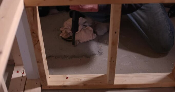 Construction worker using a powder actuated tool drives a fastener into a concrete floor with precision and skill. Selective focus