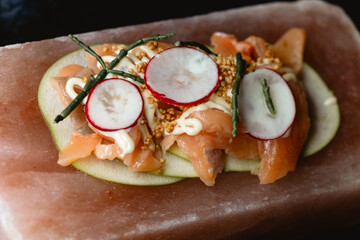 Presentation of fresh fish on a pink Himalayan salt block, served with radish