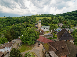 The view from Sovinec Castle in the Bruntál region shows lush greenery, rolling hills, and a quaint village below. This is the largest castle complex in the area and one of the largest in Moravia.