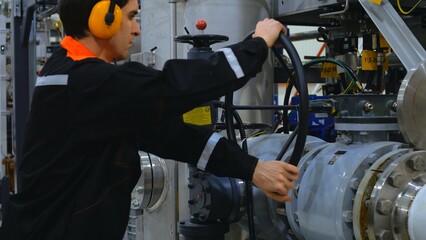 Engineer is operating large valve at industrial facility, demonstrating process. intricate process involved in valve operation. worker closes pipeline valve. Work at industrial plant