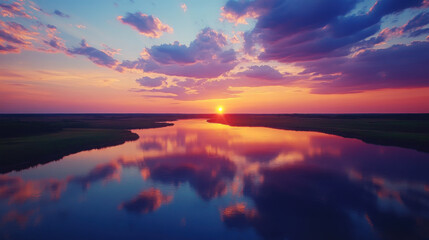 Fototapeta premium Colorful sunset over a river with dramatic sky reflections on the water