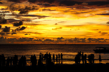 A silhouette of people at the beach during a beautiful sunset at Tanjung Aru Beach, Kota Kinabalu,...