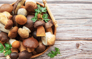 A vibrant assortment of fresh mushrooms and herbs in a woven basket on a rustic wooden table