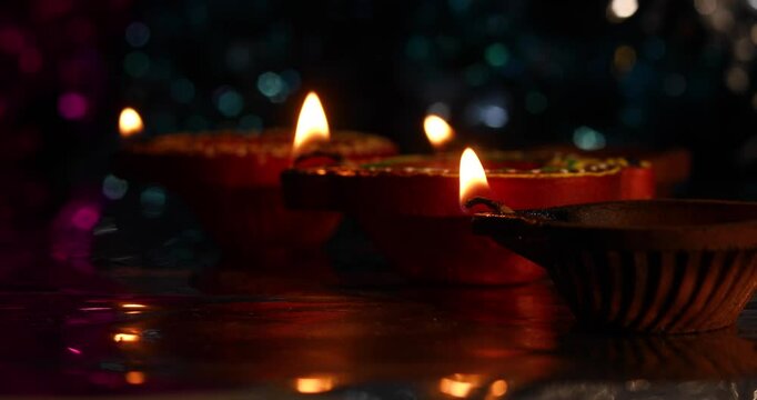 Burning clay oil lamps are lined up with light reflections on a background of bokeh effects.