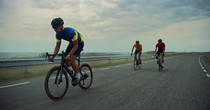 Cycling Team Pedal Together on a Quiet Coastal Road, Their Focus Sharpened as Cyclists Train Before a Big Competition. Professional Athletes Dedicated to the Sport, Pushing Forward on a Cloudy Day