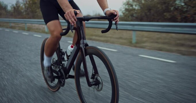 Close Up Footage of a Professional Anonymous Cyclist Speeding Along a Scenic Road, Embodying Endurance and Sporting Spirit. Solo Rider on a Thrilling Outdoor Cycling Adventures