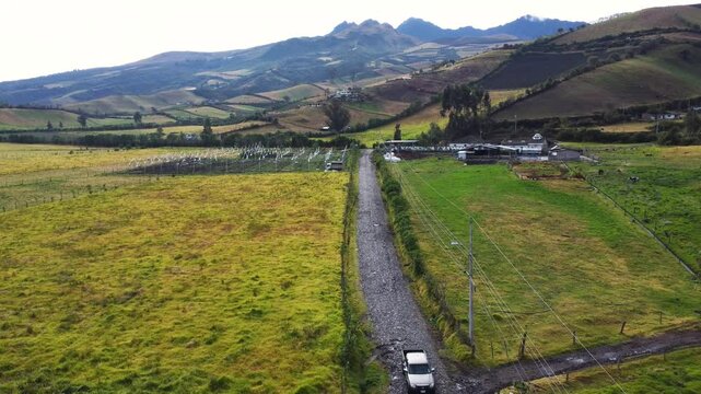 Establishing shot of a rural landscape, rolling hills, lush farmland, and a winding road in romerillo sector, Machachi parish, Mejia canton, Pichincha, Ecuador and Rumi&ntilde;ahui volcano
