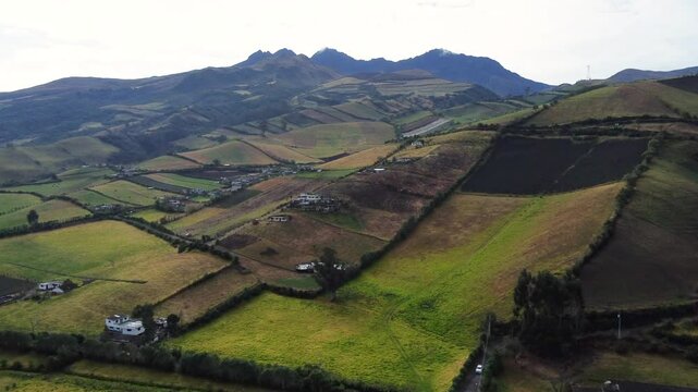 Capturing the serene beauty of rolling hills and vibrant patchwork farmland, this aerial highlights the harmonious blend of nature and agriculture in Romerillo, Ecuador and the Rumi&ntilde;ahui volcano sight