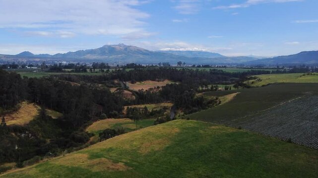 Captivating reveal aerial footage of a vast landscape in omerillo sector, Machachi parish, Mejia canton, Pichincha, Ecuador featuring lush green fields, dense forests, and distant Atacaso Vulcano