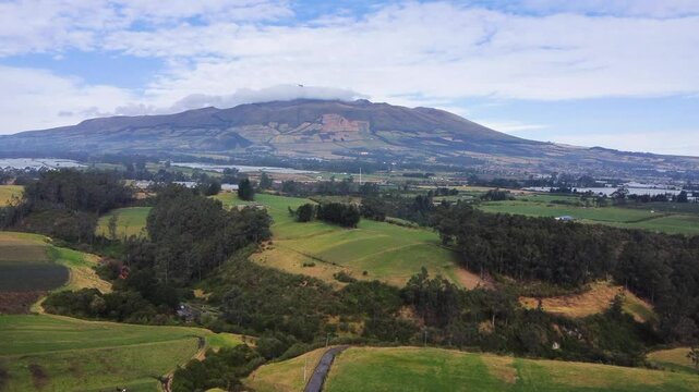 aerial view of the green landscapes of the Ecuadorian highlands in the canton of Mejia, Machachi City, Ecuador with the background of the cloudy heart volcano.