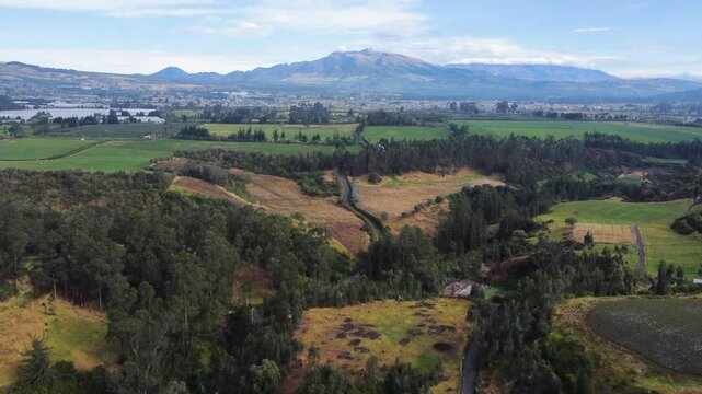 aerial view of the green landscapes of the Ecuadorian highlands in the canton of Mejia, Machachi City, Ecuador with the background of the cloudy Atacazo volcano.