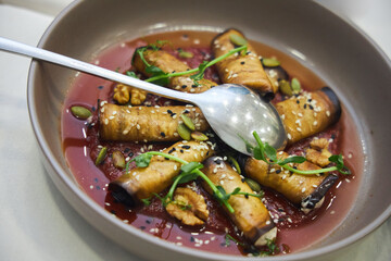 A plate of eggplant food, a spoon and a bunch of parsley. The dish is a mixture of vegetables and nuts