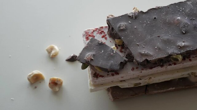 A selection of gourmet dark and white chocolate bars topped with assorted nuts on a white background.