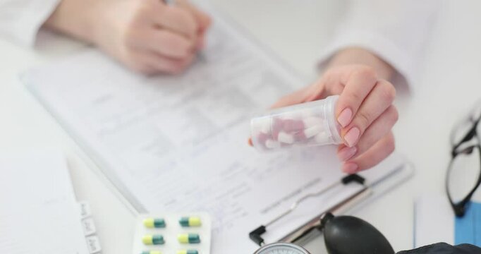 Doctor writes prescription with pills in hand