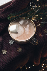 Cozy Christmas still life with hot chocolate, fir branches and lights.