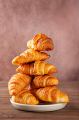 Christmas tree made of croissants in a plate on a brown background. Vertical orientation.