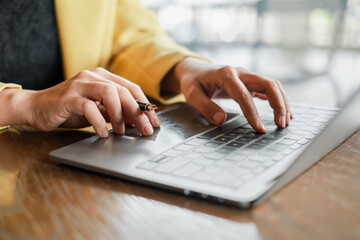 A close-up shot of hands typing on a laptop keyboard in a modern workspace, highlighting productivity and technology.