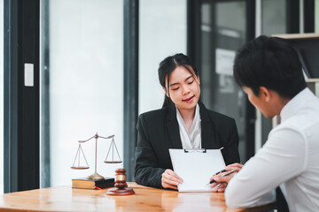 Two business professionals engaged in a discussion at a modern office, with legal scales and a gavel on the table.