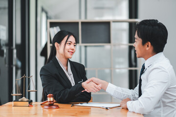 Two business professionals shaking hands across a table in a modern office, symbolizing agreement and partnership.