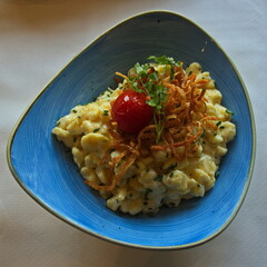 Noodles Spaetzle with cheese, roasted onion and tomato in Austria,Europe
