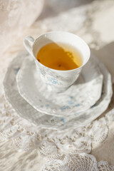 a tea cup stands with a saucer on a lace background