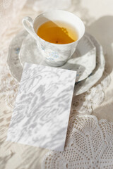 mockup of invitation against the background of a cup of tea with a saucer