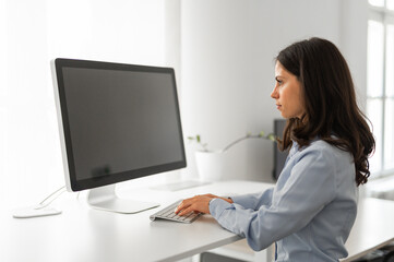 Young office worker typing on her computer, mockup screen