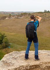 A man with a backpack is standing on a rocky hill