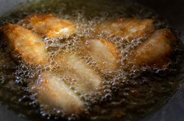 Chicken wings are fried in hot oil while frying in a pan