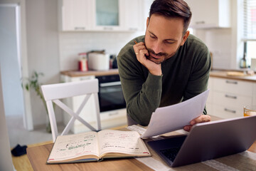 Smiling man reading motivation messages in his notebook while working at home.