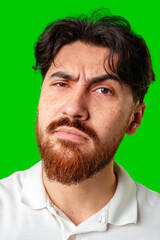 Fototapeta premium A young man with a beard showing a serious expression against a vibrant green background