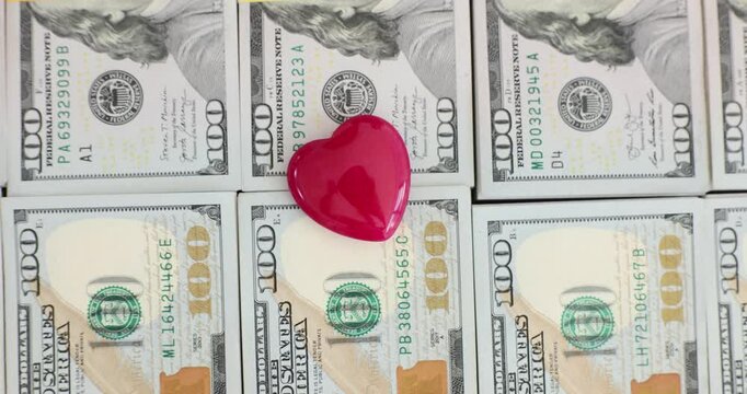 Red heart on a stack of hundred dollar bills