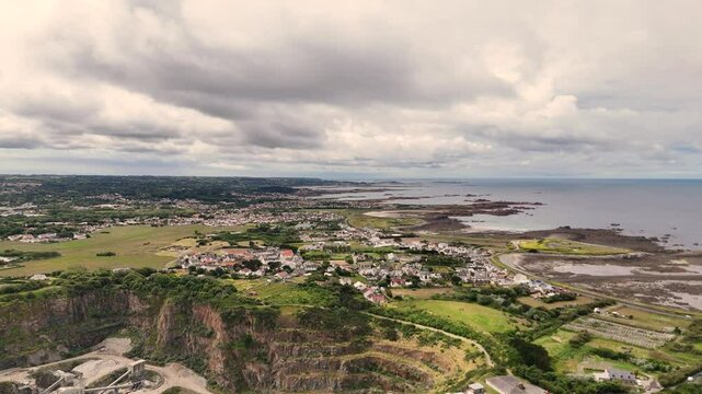 Guernsey high flight from Les Vardes Quarry towards Grandes Rocque over fields and houses showing coast road and views across to Cobo Bay and out to sea