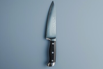 A stainless steel kitchen knife with a black handle on a light blue surface