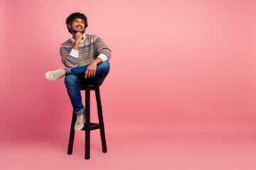 Full body photo of nice young man sit stool look empty space isolated on pink color background