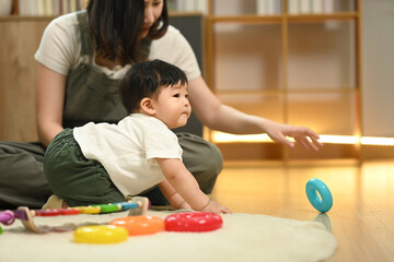 Fototapeta premium Loving young mother and cute toddler boy playing with educational didactic toy in living room