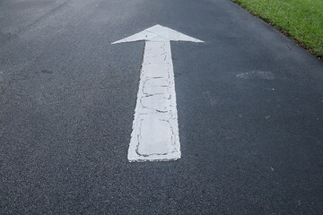 straight white arrow on asphalt