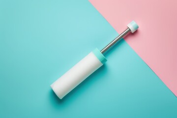 A lint roller lies on a pastel blue and pink background, ready for use in cleaning clothes or removing lint from fabric
