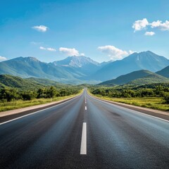 Naklejka premium A long, straight asphalt road stretches out towards a distant mountain range on a sunny day with a clear blue sky and white fluffy clouds.